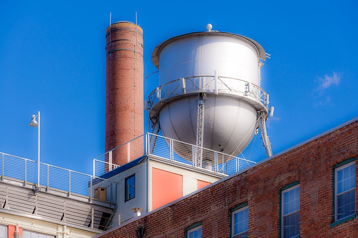 water tank and smokestack sprout in crisp winter morning light above the rooftops of brick loft buildings in Richmond’s Shockoe Bottom