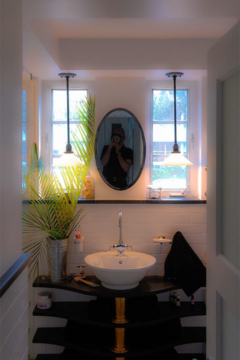 bathroom wall reflects the form of the face, with two narrow windows for eyes (lit by two pendant lights in the evening), an oval mirror for a nose, and white porcelain sink with chrome fittings for a mouth