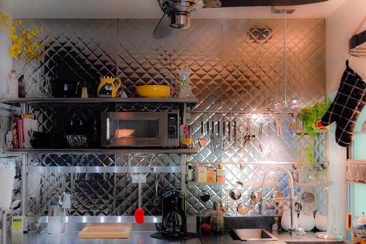 stainless steel kitchen tools and baker's rack sit against wall of pleated stainless steel panels like the ones found in classic deco diners